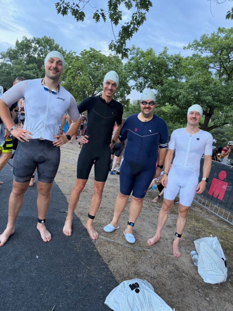 Vier Triathleten in Einteilern und Badekappen kurz vor dem Start