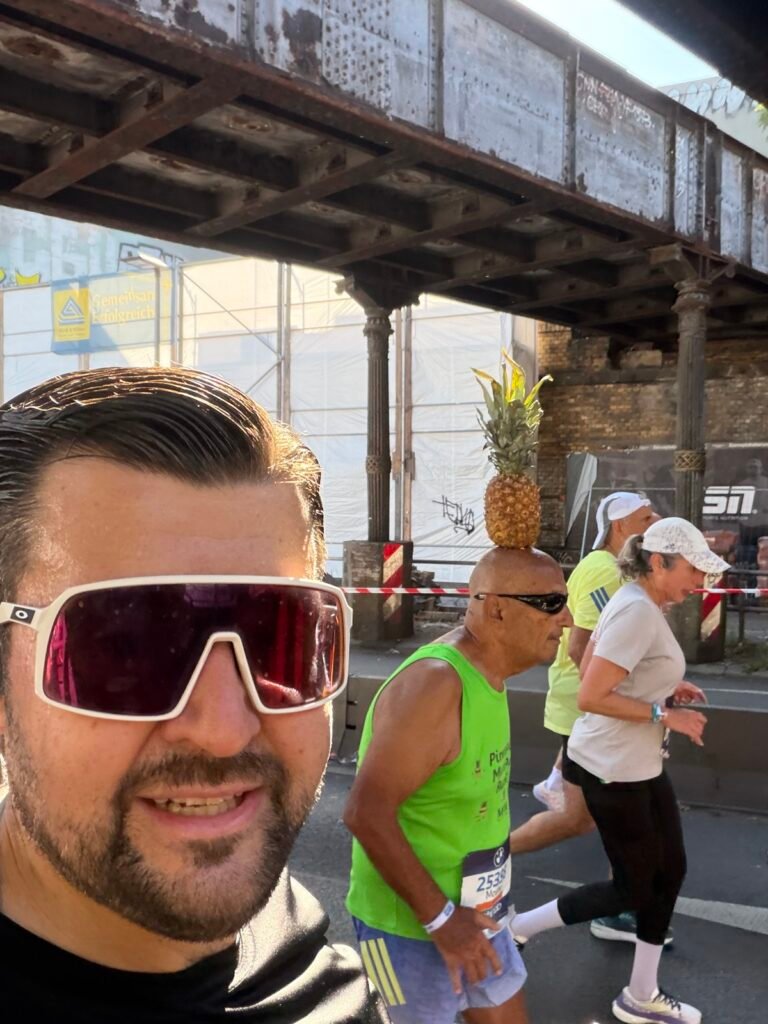 Selfie im Rennen, im Hintergrund ein Läufer mit Ananas auf dem Kopf